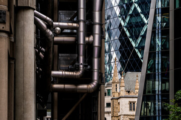 Cityscape featuring a juxtaposition of industrial pipes, modern glass architecture, and a historic building, highlighting the diversity of urban design styles in Montseny Spain