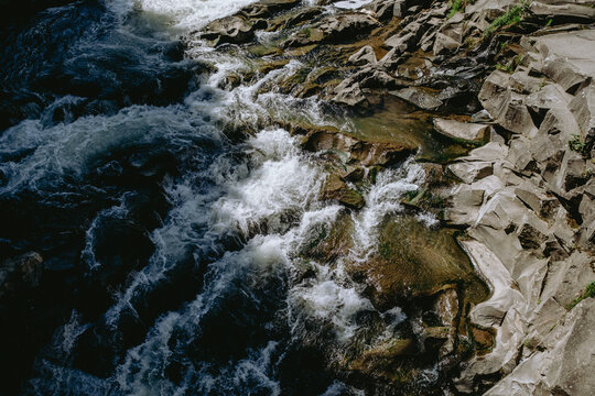 Rushing water cascading over rocky riverbed in a natural setting during daylight hours