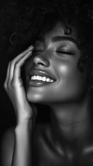 A woman with a smiling face and a hand on her cheek