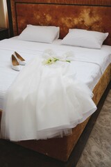 Beautifully arranged Elegant Bridal Attire resting on a bed alongside Shoes and vibrant Flowers