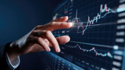 Fototapeta premium A person is touching a screen with a graph on it. The graph shows a downward trend, and the person's hand is reaching out to try to stop it