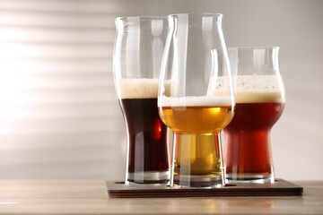 Glasses with different types of beer on wooden table indoors, closeup. Space for text