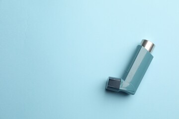 Asthma inhaler on light blue background, top view. Space for text