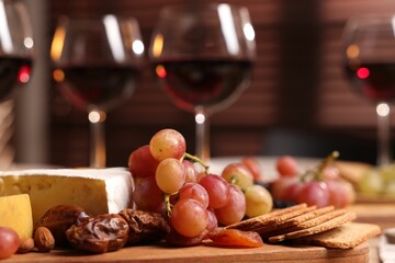 Glasses of red wine and different snacks on table, selective focus