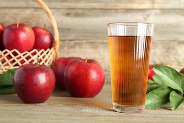 Glass of juice and apples on wooden table