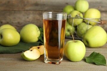 Glass of juice and apples on wooden table