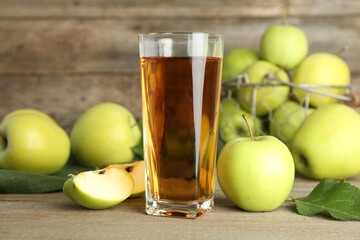 Glass of juice and apples on wooden table