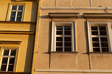 Obraz premium A bright yellow building stands alongside a tan building, creating an interesting contrast in colors next to each other in the neighborhood