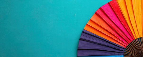 Colorful folkloric fan displayed against vibrant turquoise background, showcasing lively array of colors that evoke festive atmosphere