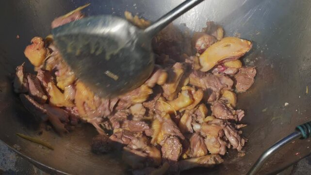 A chef is frying duck meat in a large pot