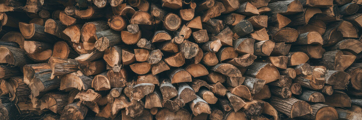 A pile of wood logs with a brownish color. The logs are stacked in a way that they are not touching each other