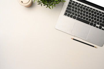 Top view laptop computer, paper cup of coffee and houseplant on white table