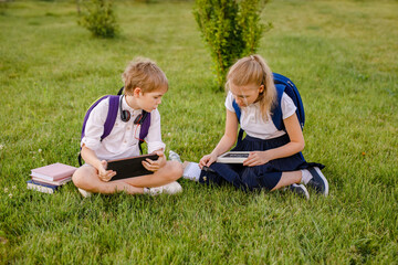 New normal: School boy and girl in the protected masks communicating and doing their homework in the schoolyard