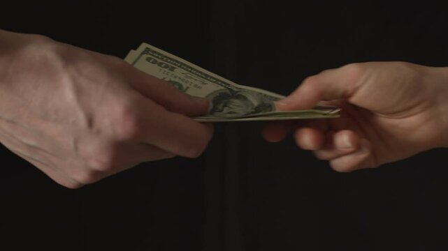 Hand giving a wad of bills with money, dollars. Concept of bribe and corruption.