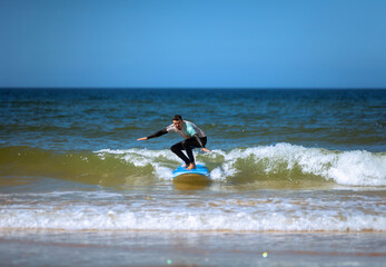 Man learning to surf on foam in the ocean. First surfing lesson. Amateur surfer. Surfing training. Photo for surfing school advertising on social media.