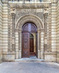 Fototapeta premium The beautifully carved wooden door of Beylar Mosque in baku, Azerbaijan, features ornate decorations and is framed by intricately designed stonework, highlighting artistic craftsmanship