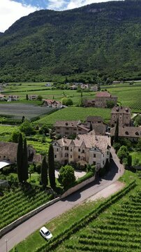 Drone video of historical Italian castle in Trentino with pool surrounded by mountains and green fields