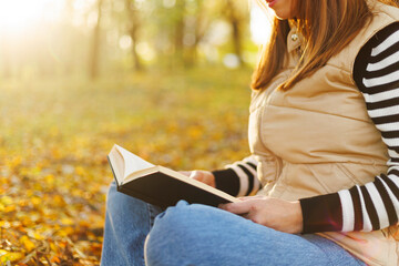 Person reading a book in autumn sunlight