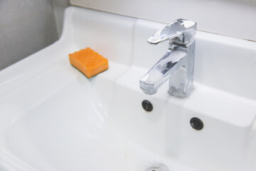 white sink in foam and cleaner, faucet and sponge, cleaning process, step 2