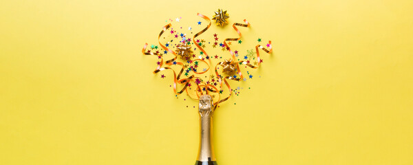Creative flat lay composition with bottle of champagne and space for text on color background. Champagne bottle with colorful party streamers. holiday or christmas concept