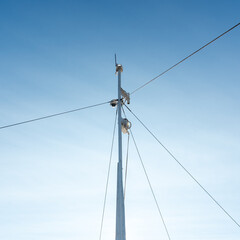 Fototapeta premium the mast of the ship with a video surveillance camera mounted on it against the background of a clear blue sky. copy pace.