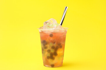 Tasty bubble tea in plastic cup on yellow background