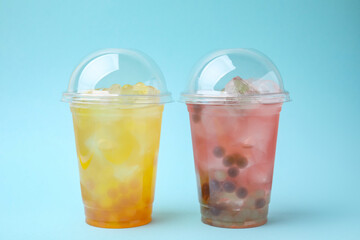 Tasty bubble tea in plastic cups on light blue background