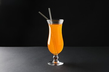 Tasty refreshing drink with straws in glass on grey table