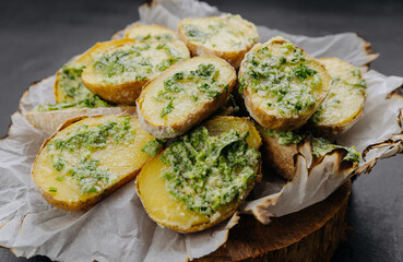 Baked potatoes with creamy herb sauce served on parchment paper, presentation for food photography