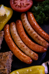 Grilled sausages with fresh vegetables and bread.  Picnic food.