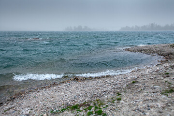 This image captures a misty and overcast scene of a river or lake during a storm