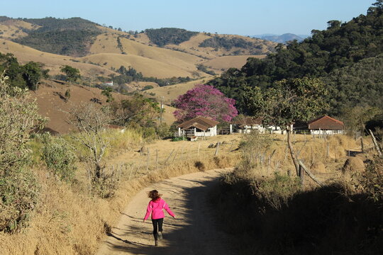mulher de casaco rosa caminhando em estrada rural na serra da mantiqueira em itamonte, minas gerais 