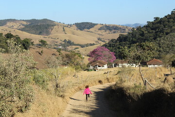 mulher de casaco rosa caminhando em estrada rural na serra da mantiqueira em itamonte, minas gerais 