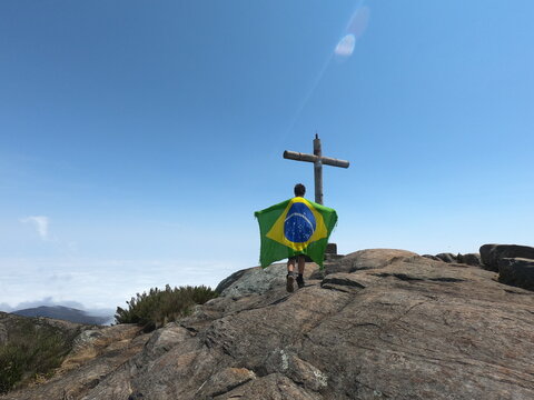 homem segurando bandeira do brasil no pico da bandeira, no parque nacional do capara&oacute;, divisa entre minas gerais e esp&iacute;rito santo 
