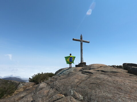 homem segurando bandeira do brasil no pico da bandeira, no parque nacional do capara&oacute;, divisa entre minas gerais e esp&iacute;rito santo 