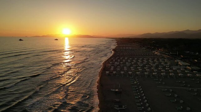 Drone video of Italian Forte dei Marmi sunset beach and sea waves, with umbrella and deck chair on the lines 