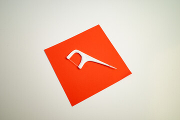 White Floss Pick on Red Paper