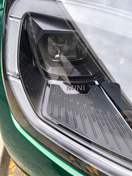 Mini logo located on the steering wheel, tires or bodywork of a Green Countryman on a street in the city of Madrid