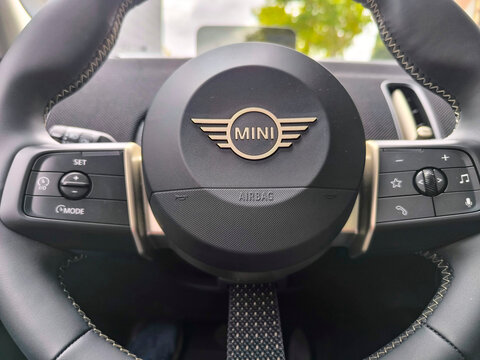 Mini logo located on the steering wheel, tires or bodywork of a Green Countryman on a street in the city of Madrid
