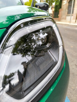 Mini logo located on the steering wheel, tires or bodywork of a Green Countryman on a street in the city of Madrid