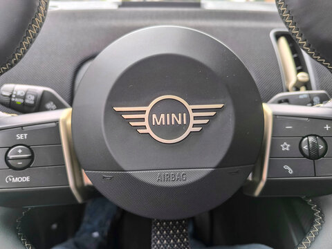 Mini logo located on the steering wheel, tires or bodywork of a Green Countryman on a street in the city of Madrid