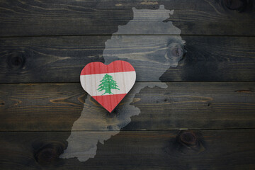 wooden heart with national flag of lebanon near map on the wooden background.