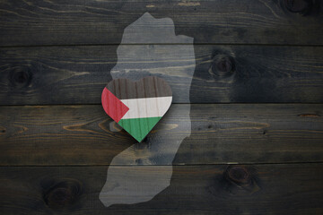 wooden heart with national flag of palestine near map on the wooden background.