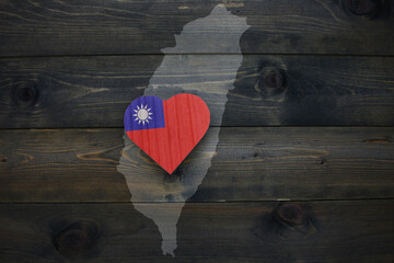 Fototapeta premium wooden heart with national flag of taiwan near map on the wooden background.