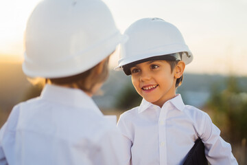 Little boys acting role of engineers or managers with safety helmet. Occupation in electrical industry, smiling smart children on electric voltage towers background