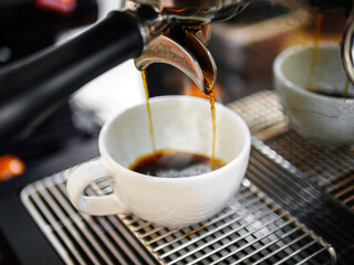 Close-up of Americano pouring from the coffee machine into a cup. Professional coffee brewing black coffee