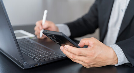 Fototapeta premium Businessman using mobile smart phone and online working on laptop computer