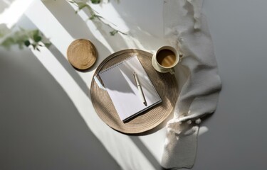 A notebook, pen, and cup of coffee rest on a woven coaster, illuminated by a window.