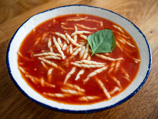 Tomato soup with trafie pasta served in bowl on wooden table
