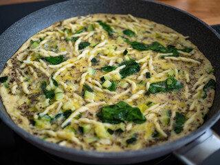 Pasta omelet - cooking scrambled eggs with mozzarella cheese, trofie noodles and spinach fry pan 